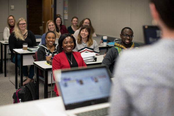 A professor lectures to a class of adult students.