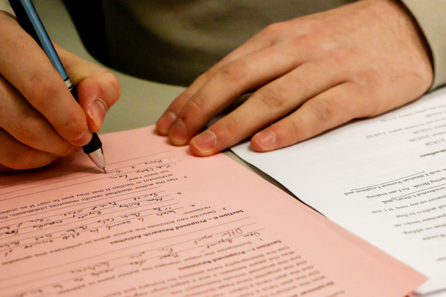 Student completing a form using a pen.