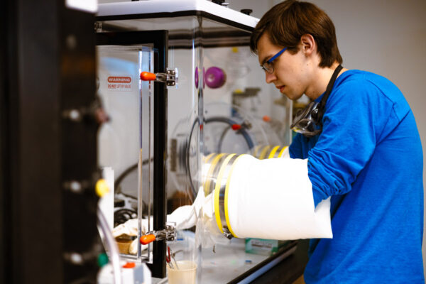 A students works carefully with equipment in a chemistry lab.