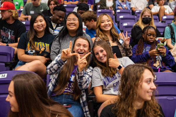 A group of students smile and pose in McCown Gym on the Winona campus.