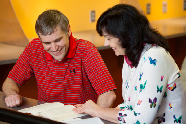 An adult student works with a tutor in an office area.