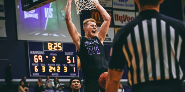 A male basketball player dunks the ball during a game at the WSU gym.