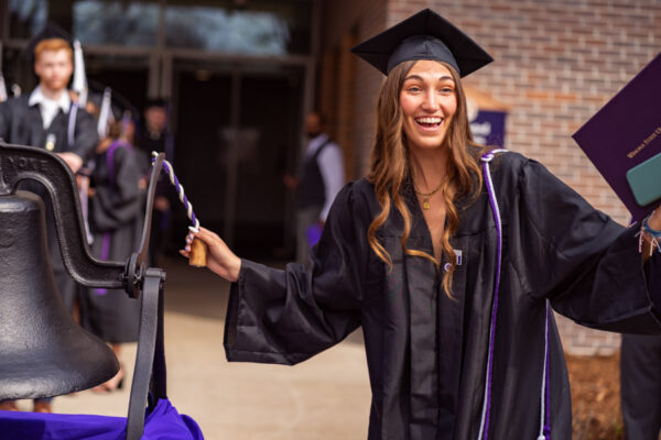 A female graduate rings the ceremonial bell after receiving her diploma during WSU Commencement.