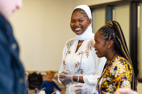 Two female students dressed in traditional cultural clothing have a conversation.