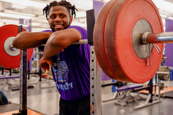 A male students leans on a bar for bench press in the WSU Fitness Center.