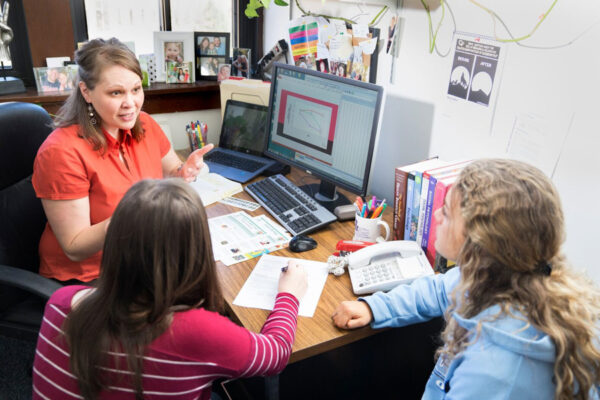 A professor meets with two students during office hours on the WSU campus.