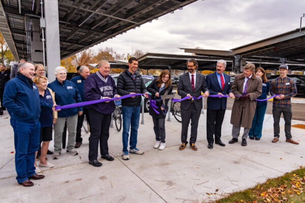 A group of people pose together for a ribbon cutting for the LESS project celebration.