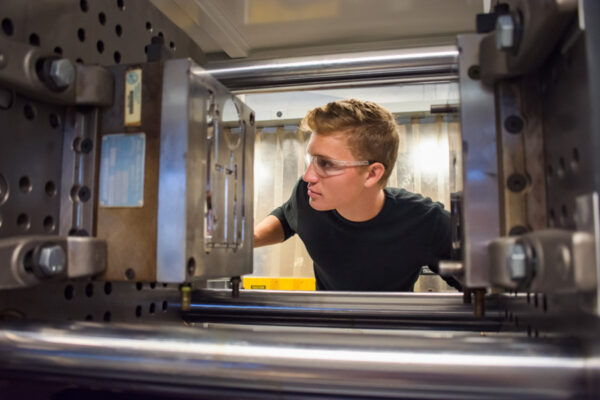 A male student at WSU examines a piece of lab equipment.