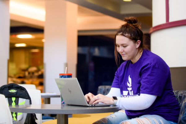 A student works on a laptop in a cafe.