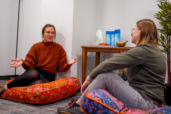 Two students talk to each other in a classroom.