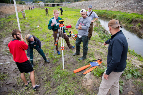 Students work together with surveying equipment during a field experience.