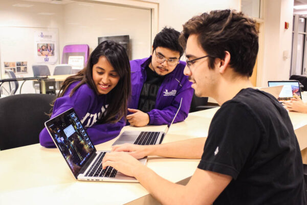 Two student workers help another student with a technical issue in the DLC.