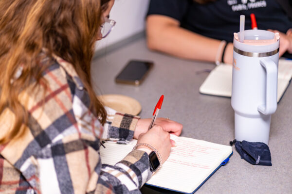 A student takes notes in a notebook.