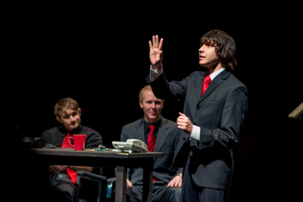 Three students perform onstage for a theater production.